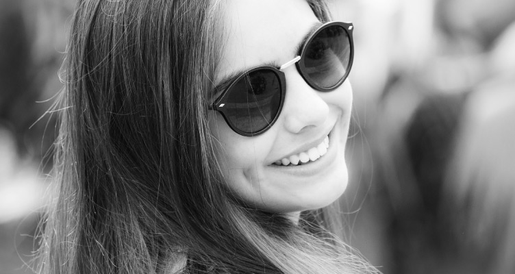 black and white photo of young girl wearing sunglasses and smiling
